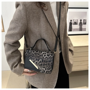 Detail view of small leopard print square bag paired with brown herringbone blazer