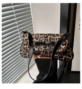 Detail of leopard print underarm bag with black leather bow and long shoulder strap