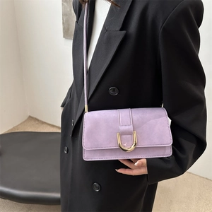 Elegante borsa baguette lilla con fibbia dorata indossata su un blazer nero