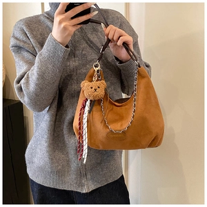 Dettaglio della borsa hobo in camoscio caramello con catena e ciondolo a forma di orsetto