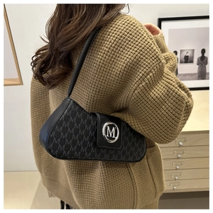 Detail of black baguette bag with letter M pattern and metal logo on a model