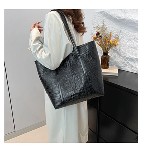 Detail of black faux crocodile skin texture and sturdy handles on large tote bag