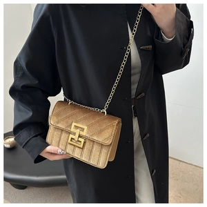 Dettaglio borsa a catena trapuntata oro con trama in velluto e chiusura geometrica elegante