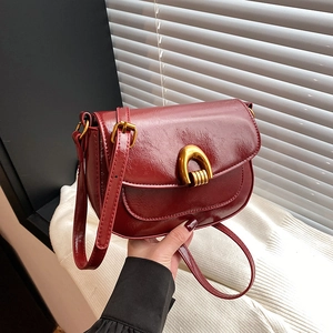 Deep red vintage saddle bag in oil wax leather with gold horseshoe buckle and strap