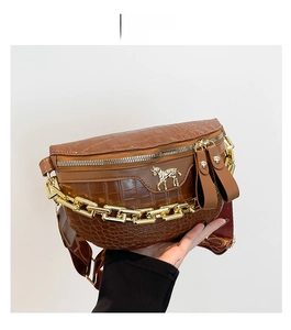 Detail der braunen Brusttasche mit Krokodilmuster, Goldkette und Pferde-Metalllogo