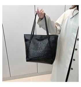 Détail d'un sac cabas noir à motif crocodile avec d'élégantes anses longues pour femme