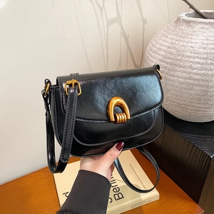 Minimalist black leather saddle bag with gold U-shaped buckle and adjustable strap