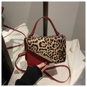 Detail of red leather crossbody bag with leopard print flap and gold metal accent