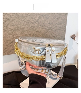 Nahaufnahme der silbernen Brusttasche in Krokodilleder-Optik mit goldenem Pferdemotiv