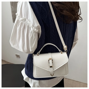 Detail of white PU leather crossbody bag featuring gold buckle and neat stitching