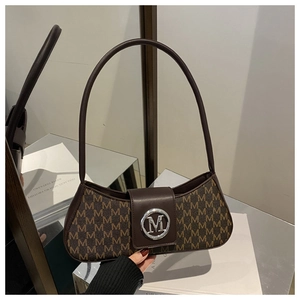 Detail of brown baguette bag with all-over M-letter print and silver metal logo