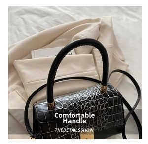 Detailaufnahme schwarze Handtasche mit Krokodilmuster, Goldverschluss und Rundgriff