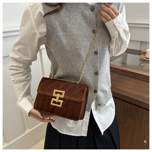 Detail of dark brown suede crossbody bag featuring gold interlocking buckle and chain strap