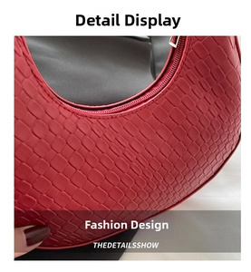 Detailed macro view of red crocodile-embossed leather texture and silver zipper of crescent bag