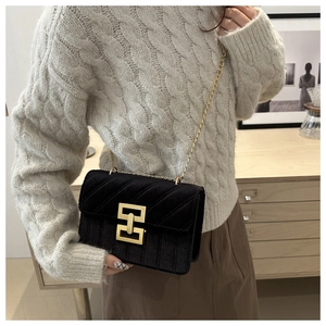 Elegante borsa a tracolla in velluto nero con fibbia dorata su un maglione grigio