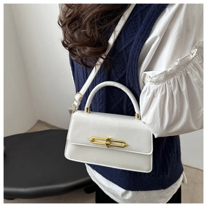 Detail of white ivory leather bag with gold metal chain lock worn by a model