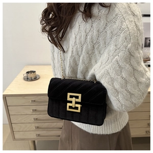 Close-up of black velvet crossbody bag featuring gold geometric buckle and chain strap