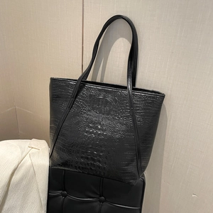 Sac fourre-tout noir à motif crocodile avec fines bandoulières sur un tabouret élégant