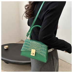 Detail der smaragdgrünen Handtasche mit Krokodilprägung, Goldverschluss und Schultergurt
