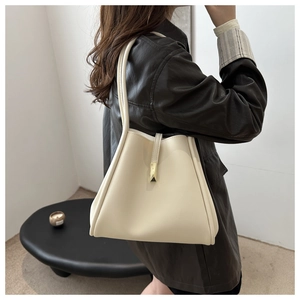Minimalist cream shoulder bag with gold buckle detail shown on model for a sleek aesthetic