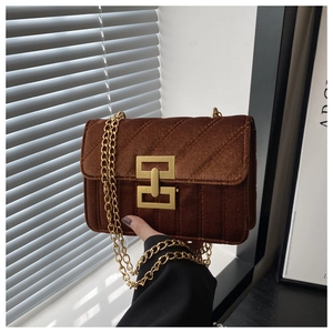 Close-up of retro brown velvet crossbody bag with gold chain and diamond quilting
