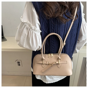 Nahaufnahme einer beigefarbenen Ledertasche mit goldenen Details und Schulterriemen