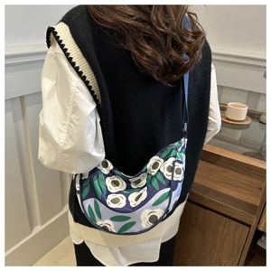 Floral crossbody crescent bag in lightweight nylon shown on model in cozy interior
