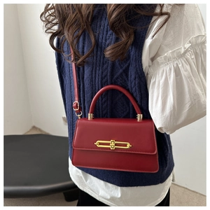 Detail of burgundy leather crossbody bag with golden clasp and adjustable strap