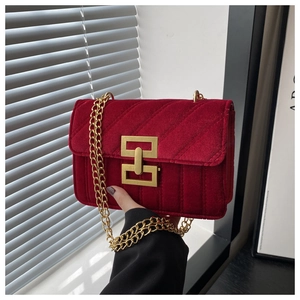 Macro shot of red velvet shoulder bag with quilted texture and gold geometric clasp