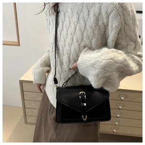Classic black leather crossbody bag with gold buckle on white knit sweater outfit