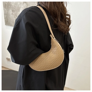 Detailed view of khaki crescent shoulder bag with crocodile pattern on a model