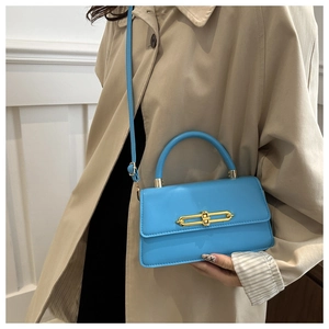 Detail of blue leather shoulder bag with stylish gold chain buckle and top handle
