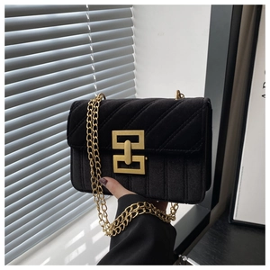 Detail of black velvet shoulder bag with gold chain and quilted geometric textures