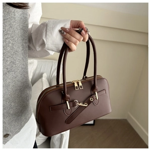 Detail of dark brown retro handbag featuring dual zippers and golden metallic hardware