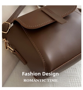 Detail of dark brown leather handbag showing matte texture and golden hardware hooks