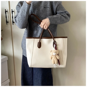 Borsa tote in ecopelle beige con manici marroni e ciondolo a forma di orsetto, vista moda