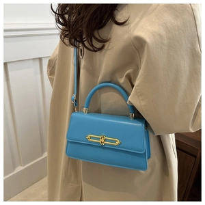 Detail of bright blue leather crossbody bag featuring gold loop clasp and top handle