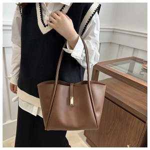 Brown leather tote bag showing actual size and style on model in a modern home setting