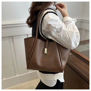 Detail einer braunen Shopper-Tasche aus Leder mit Metallschnalle und feiner Textur