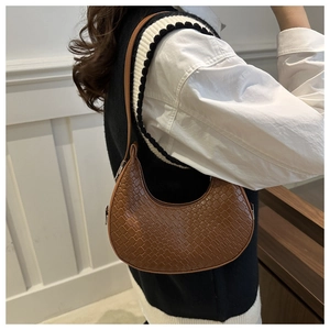 Detailed view of brown crocodile texture on a chic crescent underarm shoulder bag
