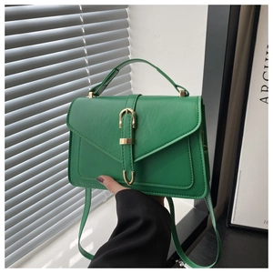 Detail of a bright green crossbody bag featuring gold buckle accents and matte texture