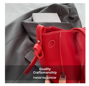 Close-up of red lychee pattern leather tote bag with white contrast stitching and knots