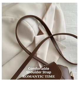 Detail of the brown leather shoulder strap with gold metal buckle and stitching
