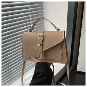 Detail of vintage beige crossbody bag with gold buckle and top handle in sunlight