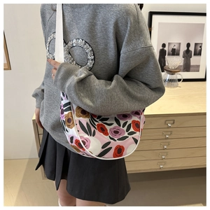 Detailed view of the colorful floral print canvas saddle bag with wide white fabric strap