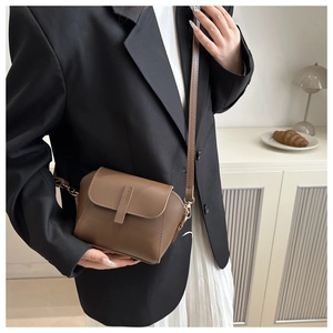 Detail of vintage brown leather crossbody bag with golden hardware on a shoulder model
