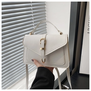 Detailed view of the white crossbody bag featuring a golden buckle and envelope flap