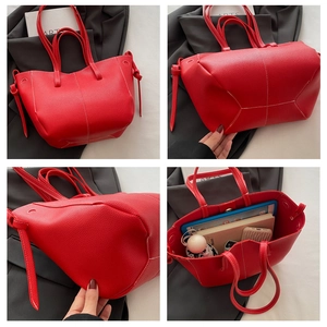 Close-up of red pebbled tote bag showing spacious interior with white contrast stitching