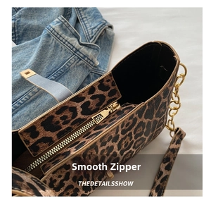 Close-up of smooth gold metal zipper and chain strap on leopard print shoulder bag