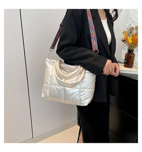 Sac cabas argenté matelassé avec bandoulière géométrique porté par un mannequin femme